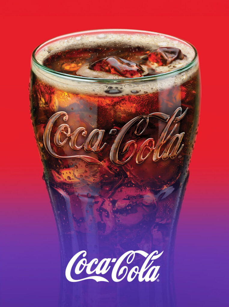 Ice-cold glass of Coca-Cola with condensation on red background